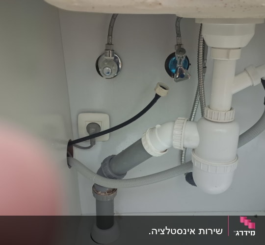 צנרת מתחת לכיור עם חיבורים וצינורות